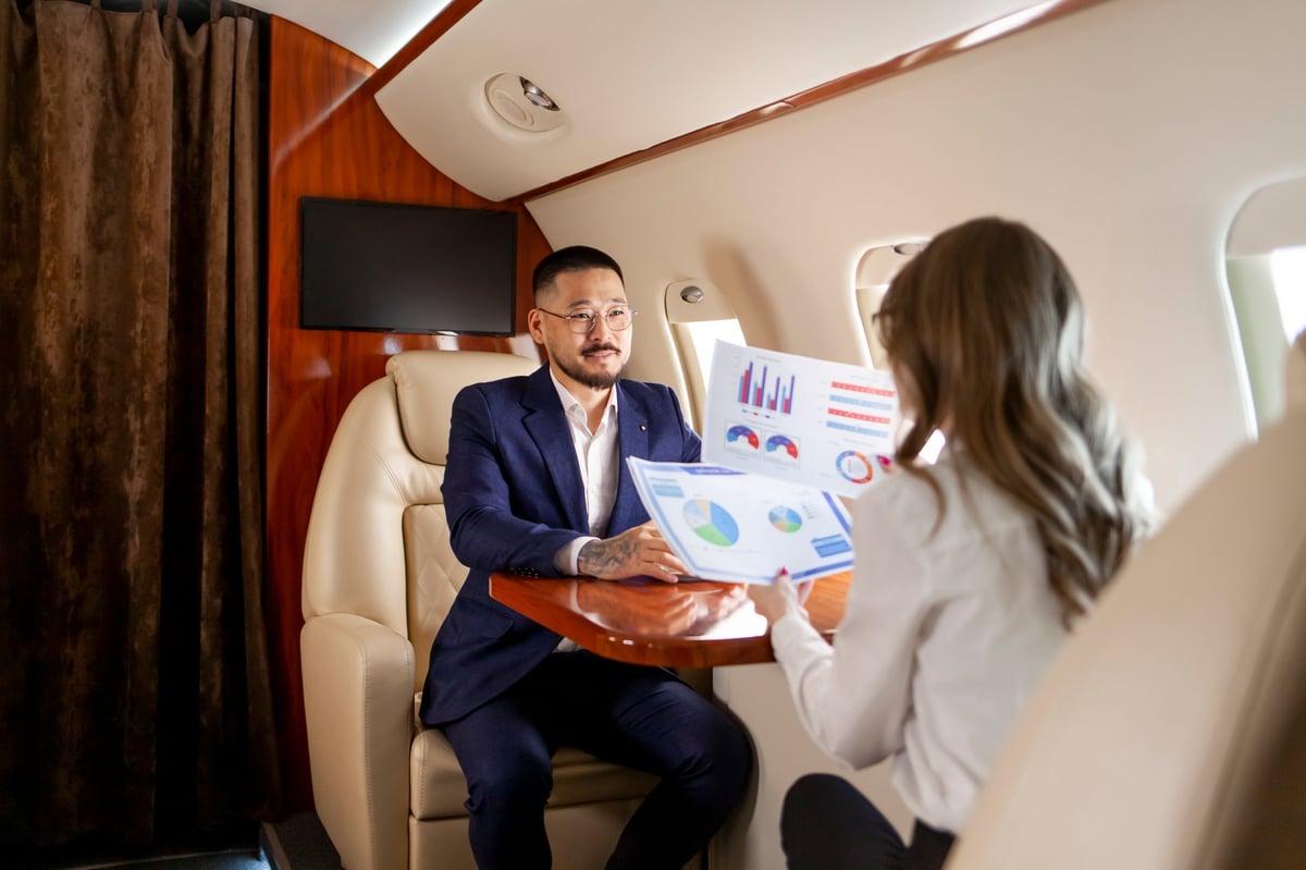 A dedicated assistant reviewing documents with a client aboard a private jet