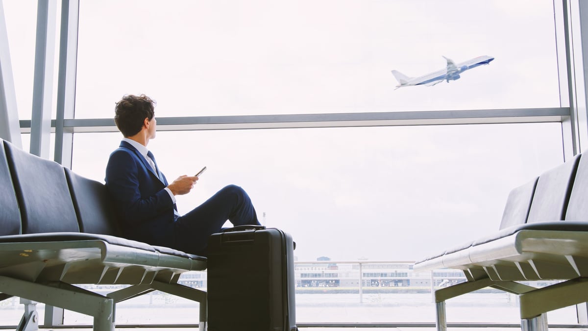 Business leader in a departure lounge watching a plane take off
