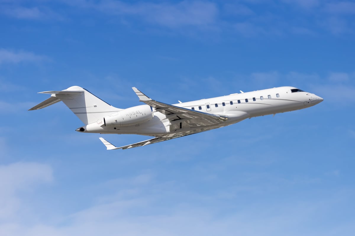 An ultra-long-range business jet banking over a coastline at golden hour